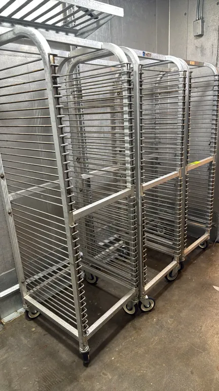 Aluminum front-load pan racks. Features aluminum tube construction with multi-tier wire slides for standard sheet pans. Mounted on swivel casters.