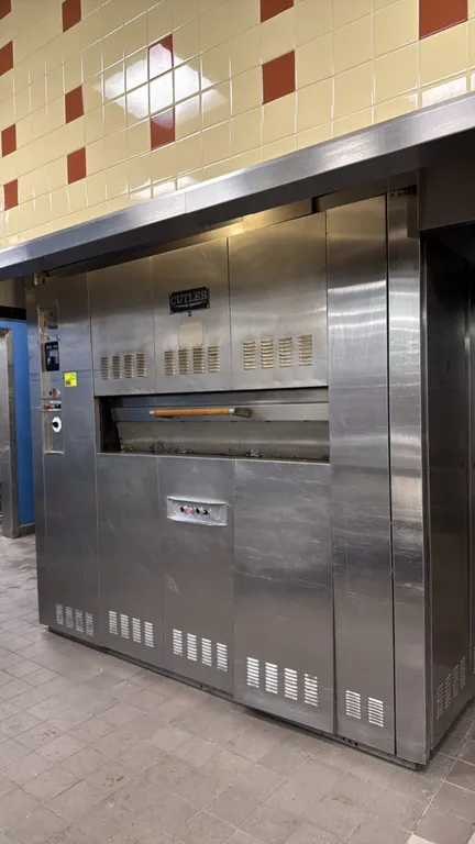 Cutler PNL-15 15-pan revolving deck oven. Features stainless steel construction, 5-shelf revolving mechanism, analog temperature controls, and timer.