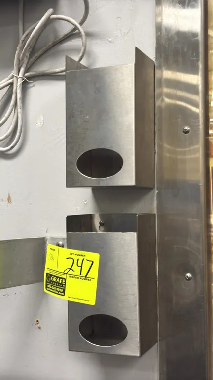 Stainless steel hair net racks. Includes (2) dispensers featuring top-loading design and oval front dispensing openings. Wall-mount design.