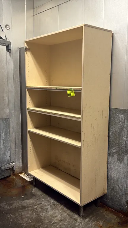 Laminate merchandiser rack. Features tan laminate finish, three adjustable shelves, and a bottom shelf deck. 43" x 79". Mounted on metal legs.