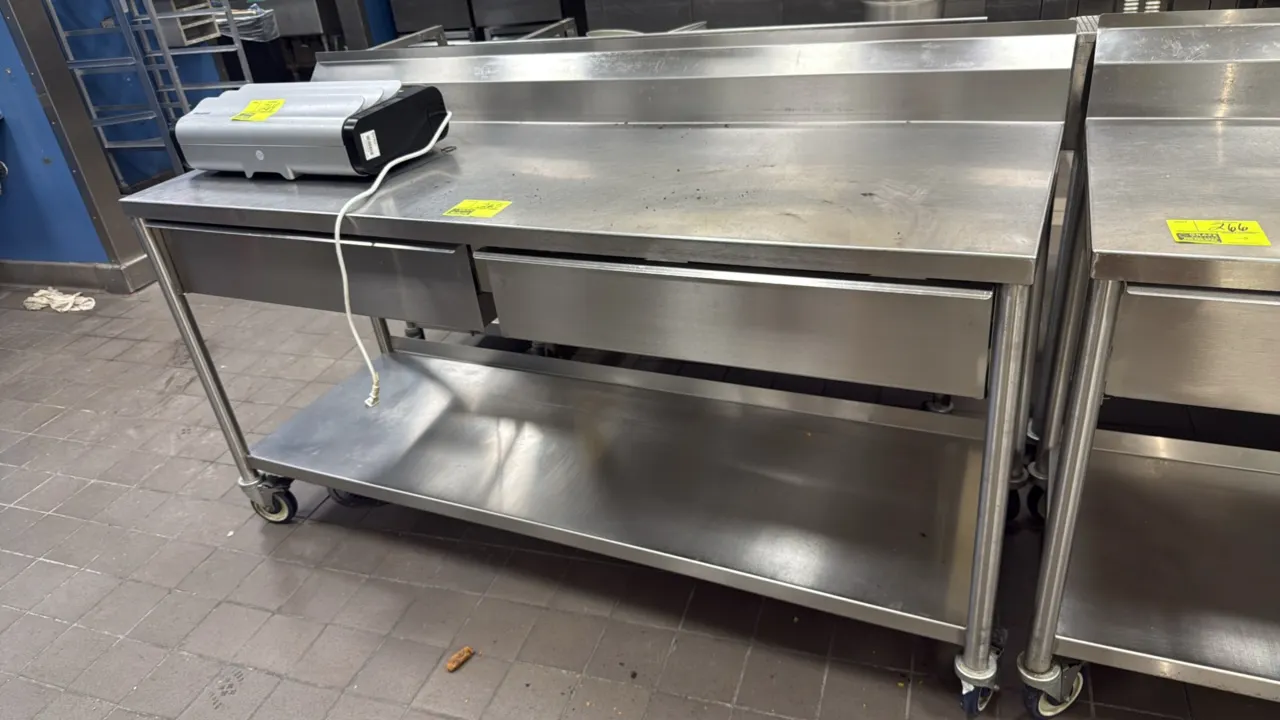 Portable stainless steel work table. Features a rear backsplash, (2) sliding drawers, and an undershelf. Measures 72" x 24". Mounted on casters. Table