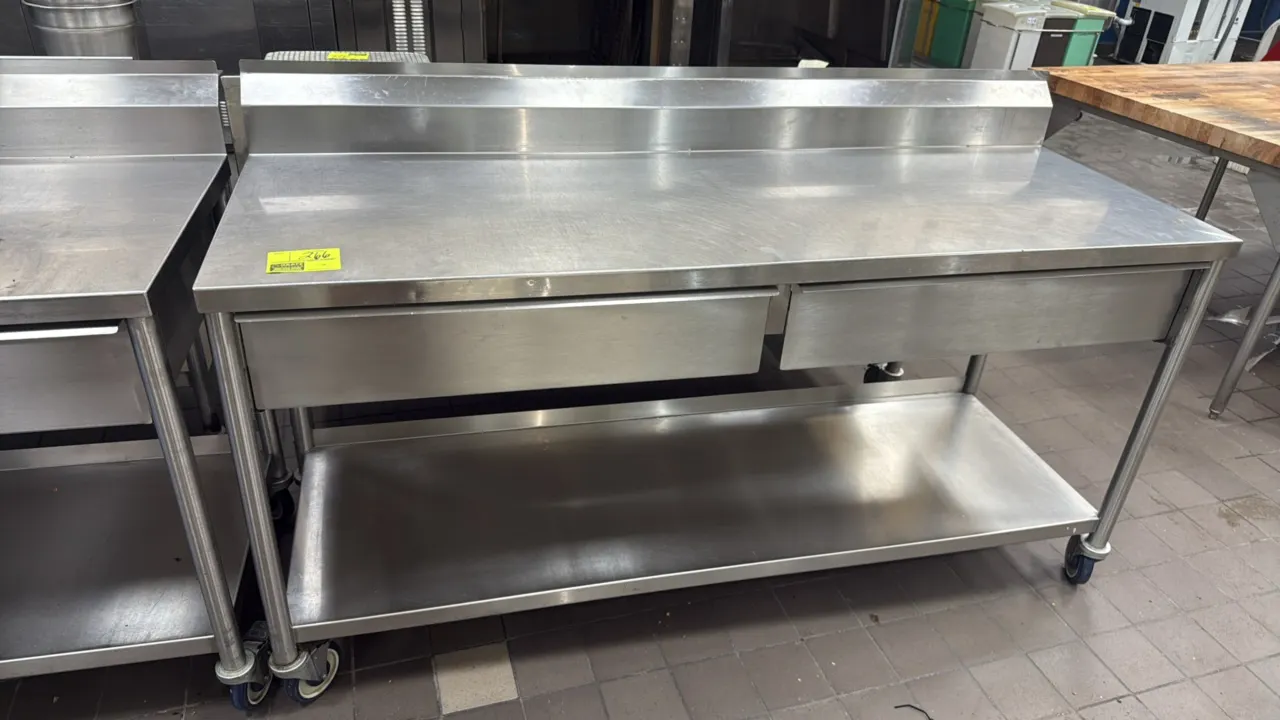 Stainless steel work table. Features an integrated backsplash, (2) drawers, and a solid undershelf. Measures 72" x 24". Mounted on casters.