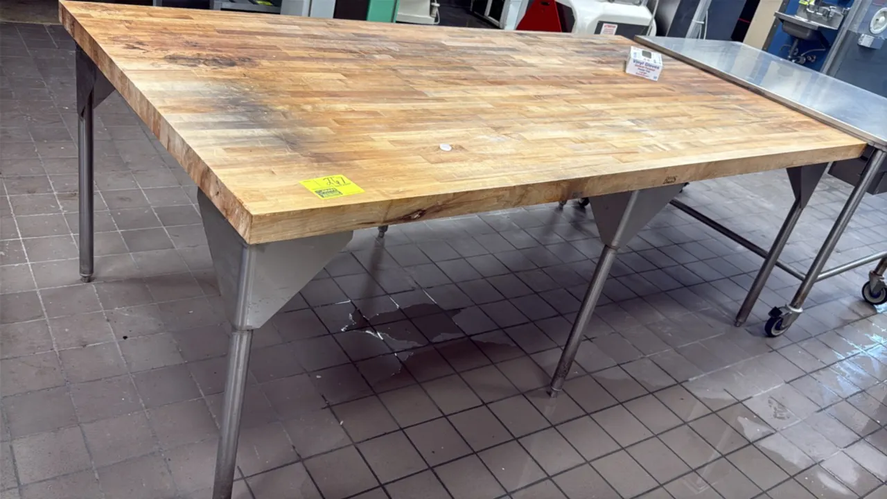 Butcher block work table. Features a laminated hardwood butcher block top and stainless steel tubular legs with gusset supports. 96" x 48.5". Mounted