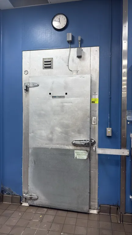 Kysor walk-in freezer. Features insulated foam panels, diamond plate flooring, hinged entry door with vinyl strip curtains, interior lighting, mounted