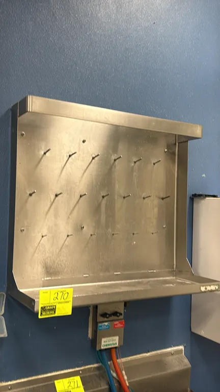 Stainless steel wall-mount tool rack. Features 19 hanging pegs, an integrated bottom shelf, and an upper guard rail. 30"W. Wall-mount design. Note: Si