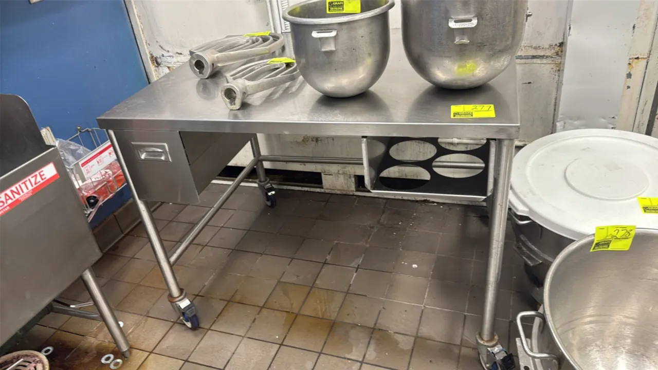 Portable stainless steel table. Features a single left-side drawer, under-counter organizer rack, and tubular legs with three-sided cross bracing. 48"