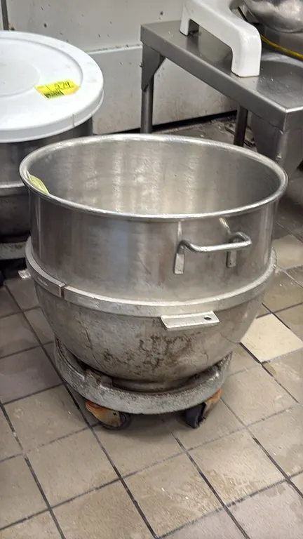 Varimixer VML 80 80-quart stainless steel mixer bowl. Features dual side lift handles and mounting brackets. Includes caster-mounted rolling bowl doll