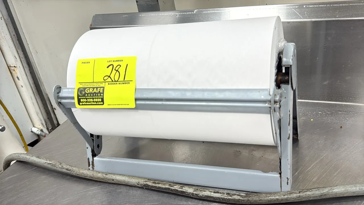 12" paper roll rack dispenser. Features a gray metal frame and integrated cutter bar. Includes paper roll as shown.