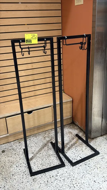 Metal floral bag stands. Features black tubular steel construction, upper hanging brackets with hooks for floral sleeves, and freestanding rectangular