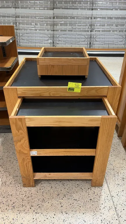 Wood produce dump bin. Features oak-look wood construction with black inset display surfaces, a pull-out lower tiered display shelf, and an upper disp