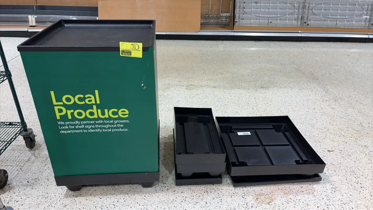 Corrugated produce stump bin display. Features green "Local Produce" graphic wrap, black plastic top tray, and molded base. Includes additional assort