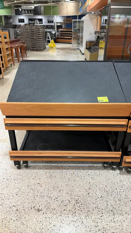 Produce tilt display tables. Features slanted display decks with wood-grain finish front retaining lips, lower storage shelves, and integrated protect