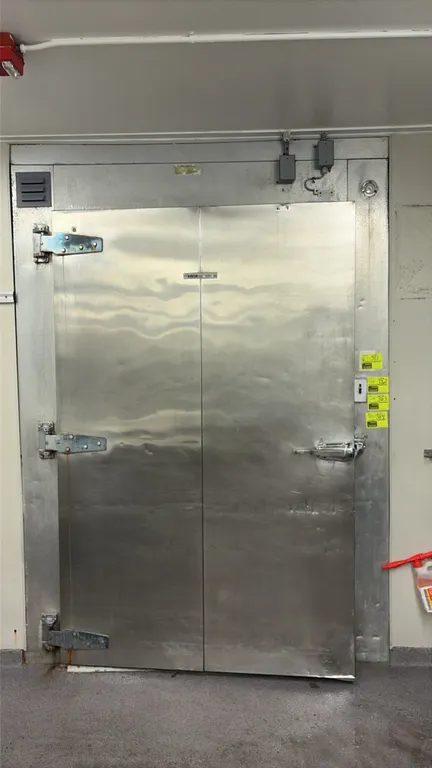 Walk-in freezer. Features Larkin 5-fan evaporator, diamond plate flooring, interior lighting, wall-mounted shelving, and heavy-duty hinged entry door.
