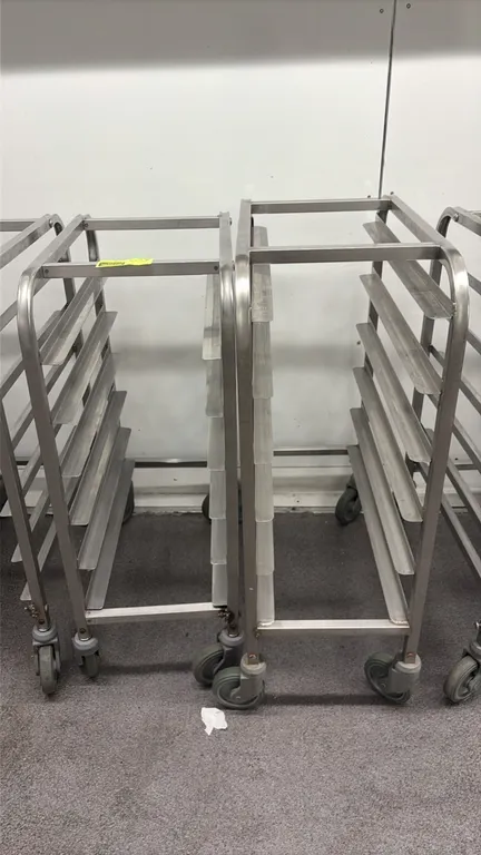 Stainless steel half-size pan racks. Features 6-tier slides and tubular frame construction. Mounted on swivel casters.
