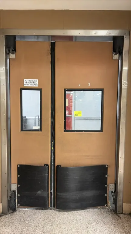 Double swing poly impact traffic doors. Features rectangular vision panels and lower black kick plates. Door panels measure 36"W x 92"H and 22"W x 92"
