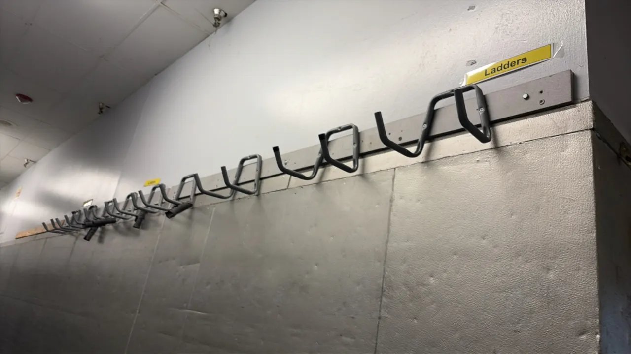 Wall-mounted hose racks. Features tubular metal storage hooks mounted along wall backer boards.