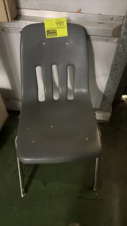 Poly stacking chair. Features a gray molded plastic shell with vertical back slots. Mounted on a chrome tubular metal 4-leg base with floor glides.