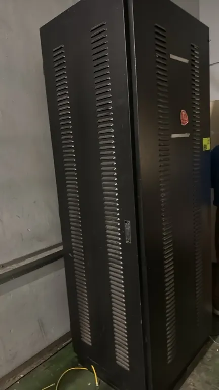 Enclosed metal IT server rack cabinet. Features front and rear louvered doors, internal mounting rails, patch panels, and cable management. 26" x 30"