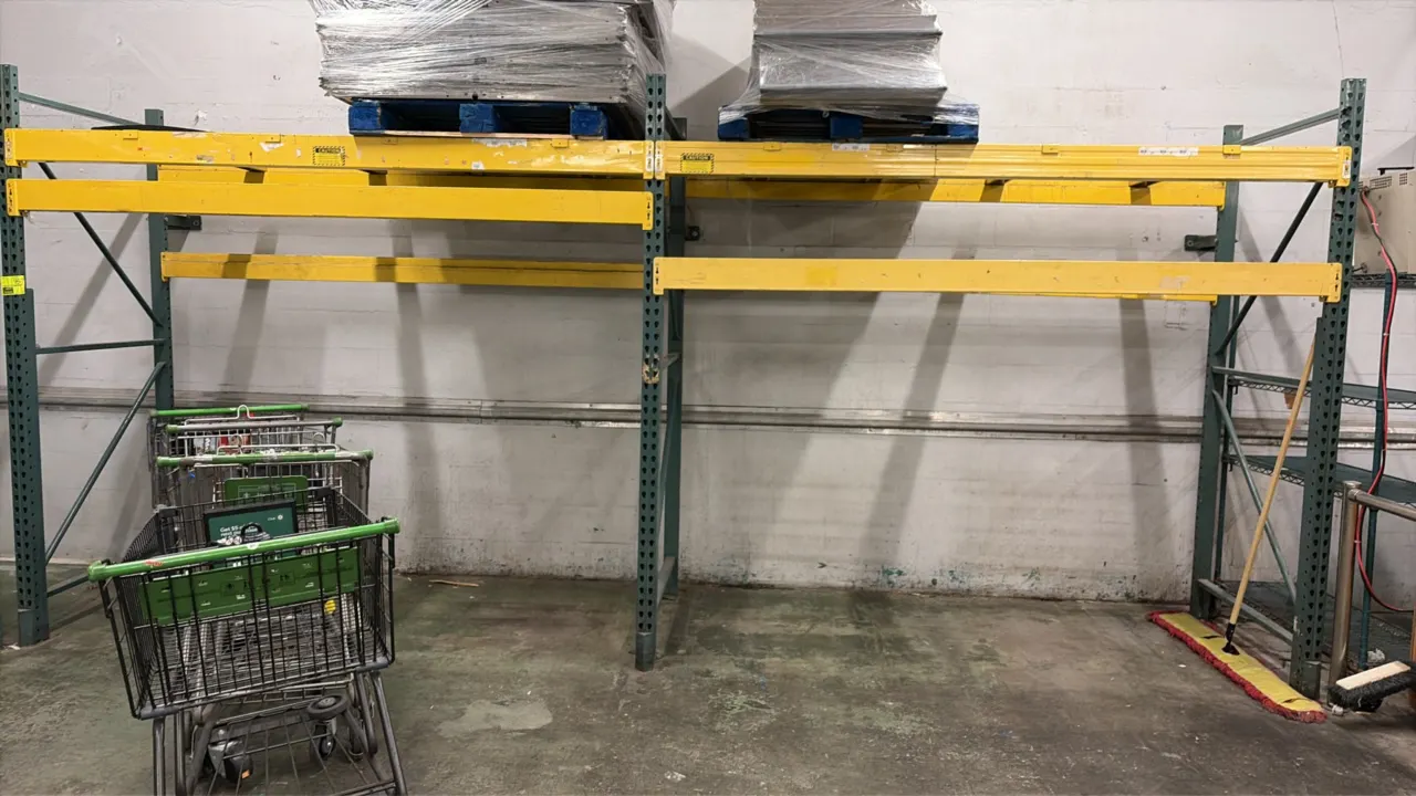8'L of warehouse pallet racking. Features green upright frames, yellow load beams, and pallet support bars. 8'L x 42"D x 8'H. Contents and surrounding