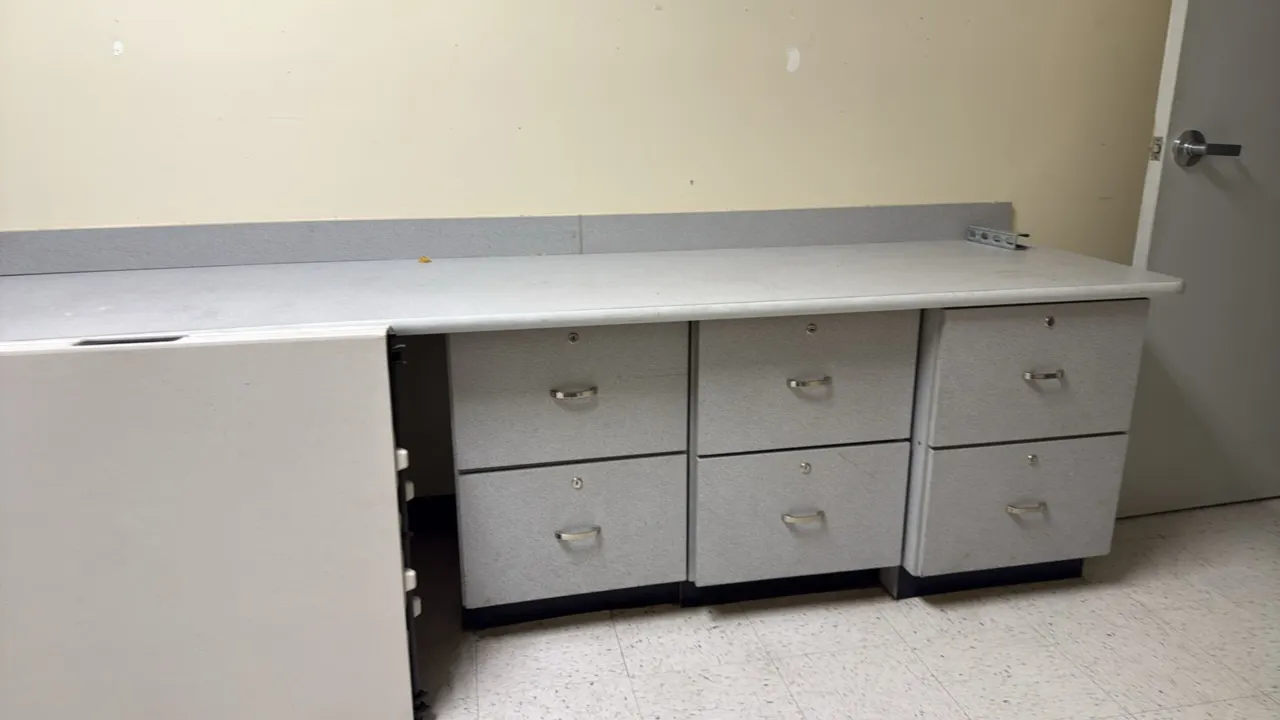 Laminate countertop with base cabinets. Features a grey laminate work surface with matching backsplash, base cabinets with drawer storage, and silver-