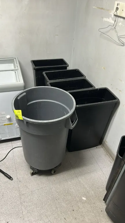 Assorted poly trash bins. Includes (1) round gray commercial trash container mounted on a rolling caster dolly base, (4) tall rectangular black plasti