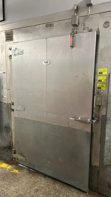 KPS Global walk-in freezer. Features insulated foam panels, pallet-sized swing door with kick plate, diamond plate flooring, strip curtains, interior