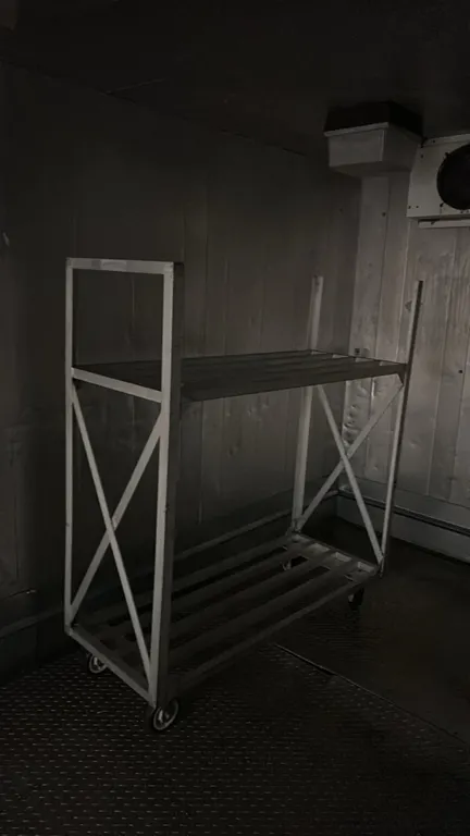 Aluminum 2-tier cart. Features welded tubular aluminum construction, slatted shelves, and cross-braced side supports. 5' x 2'. Mounted on casters.