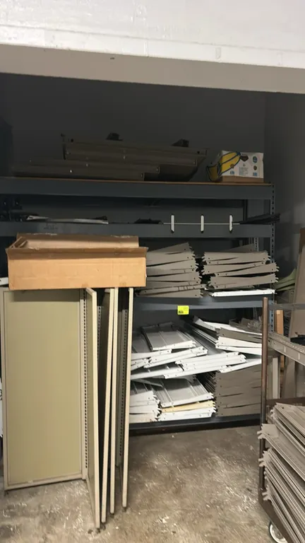 Assorted retail shelving components. Includes metal shelves, uprights, base brackets, backing panels, and related shelving hardware. Note: Rolling sto