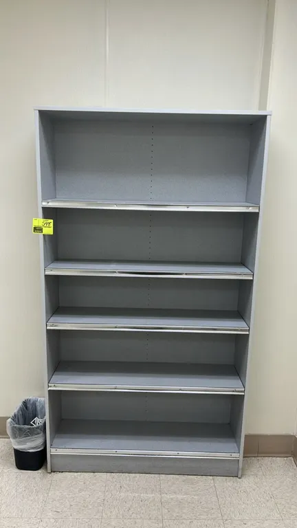 Laminate multi-tier bookcase shelving unit. Features a gray laminate finish, adjustable shelving with pre-drilled pin holes, and metal shelf edge trim