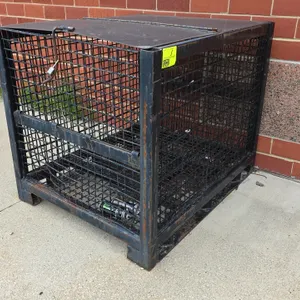 Metal wire mesh storage container. Features welded steel wire construction, hinged solid metal top lid, front drop gate, and forklift-compatible base 
