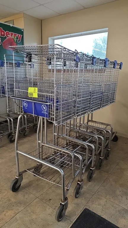Over-the-counter wire shopping carts. Features upper wire basket, child seat with blue plastic flap, lower wire parcel tray, blue protective corner bu