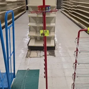 Metal rotating merchandiser display rack. Features red painted finish, 2 spinning wire hook tiers, center pole clip strip hangers, round base, and top