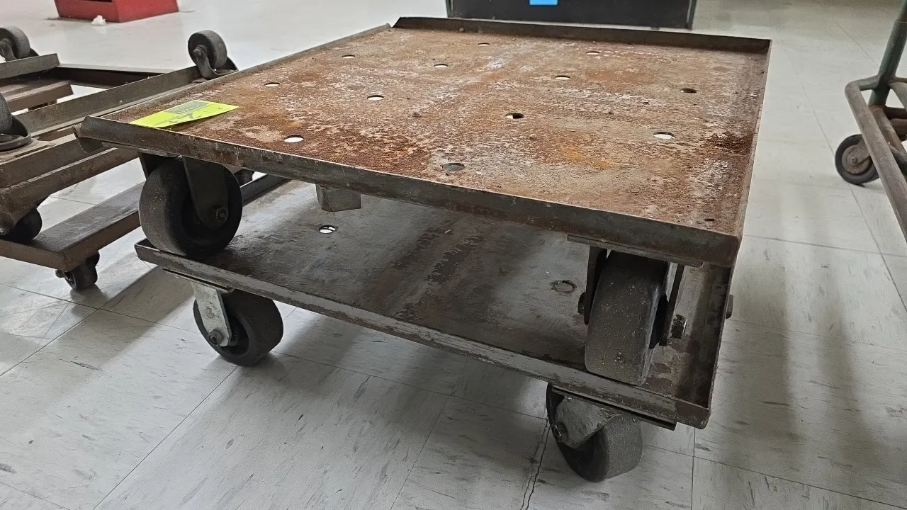 Metal 4-wheel platform dollies. Features steel construction with upturned lip edges and perforated decks. 27" x 27". Mounted on (4) casters. Note: Exh