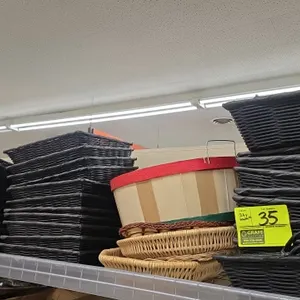 Assorted retail display baskets. Includes black woven rectangular baskets and handled trays in various sizes, natural woven round display baskets, and