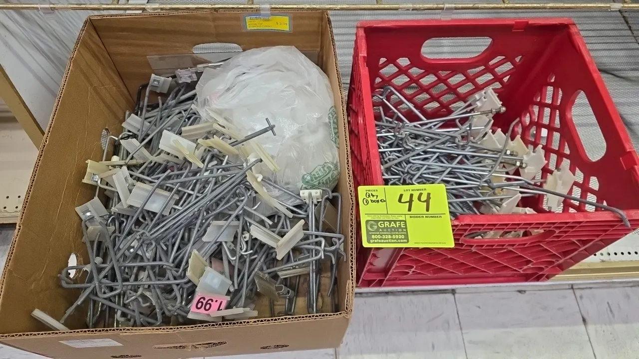 Assorted metal pegboard display hooks. Features wire scanner hooks with plastic label holders. Lot includes (1) cardboard box and (1) plastic crate.