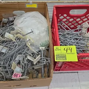 Assorted metal pegboard display hooks. Features wire scanner hooks with plastic label holders. Lot includes (1) cardboard box and (1) plastic crate.