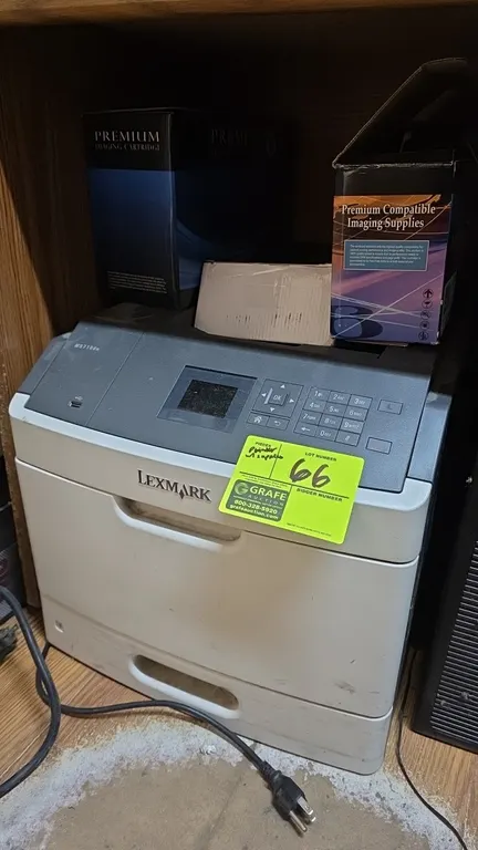 Lexmark MS710dn monochrome laser printer. Features digital control display with numeric keypad, front USB port, and integrated paper cassette tray. In