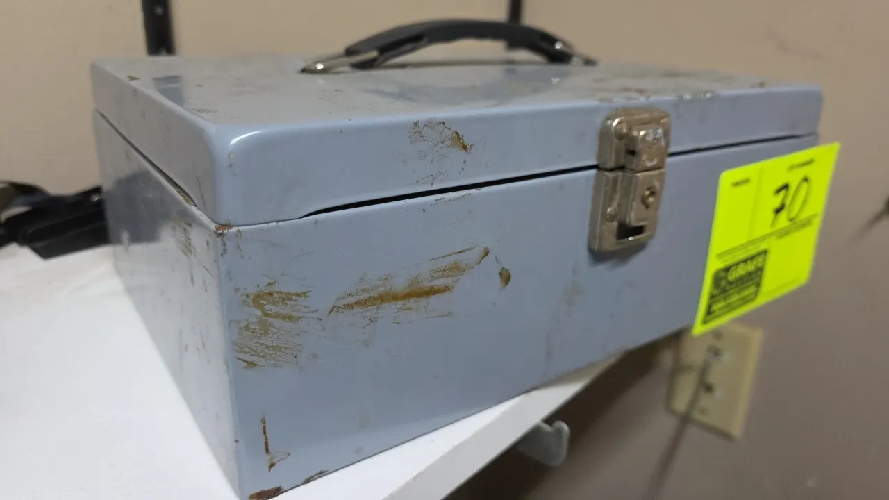 Metal cash box. Features a fold-down top carrying handle, front latch with keyhole lock, and 4-compartment interior tray with spring-loaded bill clips