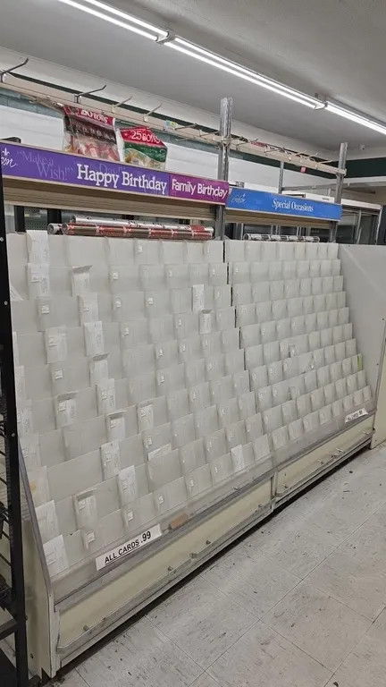 Gibson greeting card display racks. Features multi-tier slotted display rows, bottom pull-out storage drawers, and overhead gift wrap racks with displ