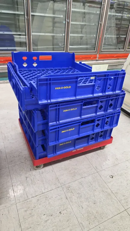 Pan-O-Gold blue poly stackable bread trays. Features open grid bottoms, integrated side handles, and interlocking stacking design. Includes 4-wheel ca