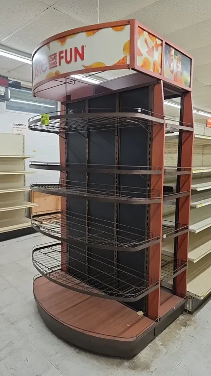 Portable end cap merchandiser display rack. Features multi-tier curved wire shelves with front retaining lips, side shelving, lower woodgrain-style ba
