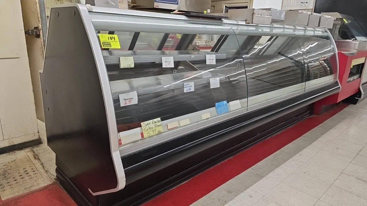 2017 Hussmann SMB-12 curved-glass remote deli case. Features curved front glass, rear sliding service doors, tiered stainless steel shelving, and inte