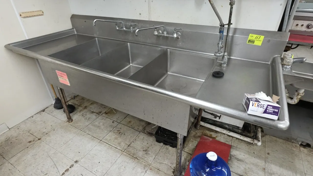 Stainless steel 3-compartment deep well sink. Features left and right drainboards, integrated backsplash, (2) splash-mount swing-spout faucets, and de