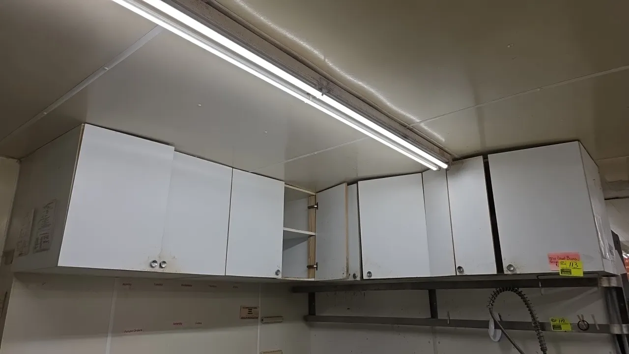 Laminate wood L-shape upper cabinets. Features white laminate construction, hinged cabinet doors with round metal knobs, and interior storage shelving