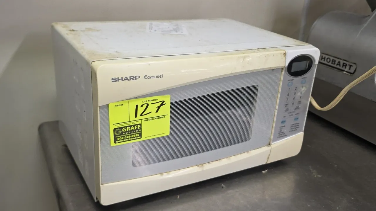 2009 Sharp Carousel R-230KW countertop microwave oven. Features glass turntable with roller ring, digital display, and touchpad controls with preset c