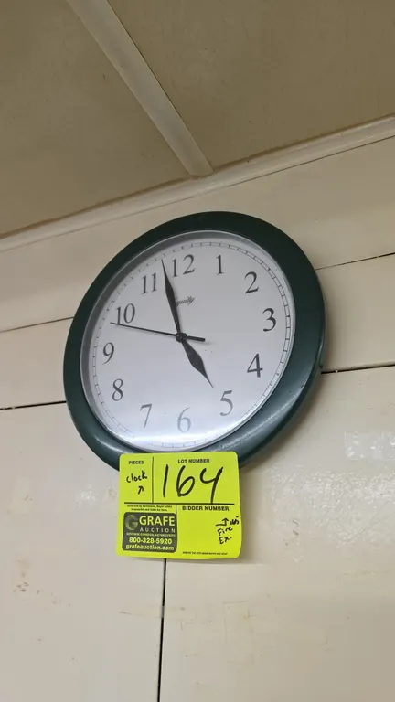 Equity 25205 battery-operated quartz wall clock. Features an analog display with Arabic numerals and a round green frame. 9.75" Dia. Keyhole slot for