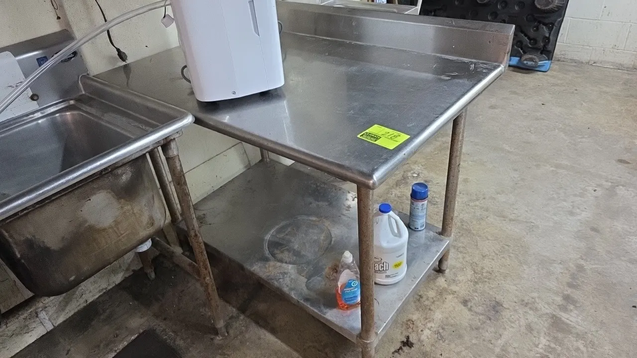 Stainless steel work table. Features rear and right-side splashes, stainless undershelf, and adjustable bullet feet. Dimensions: 48"L x 30"W. Note: Ho