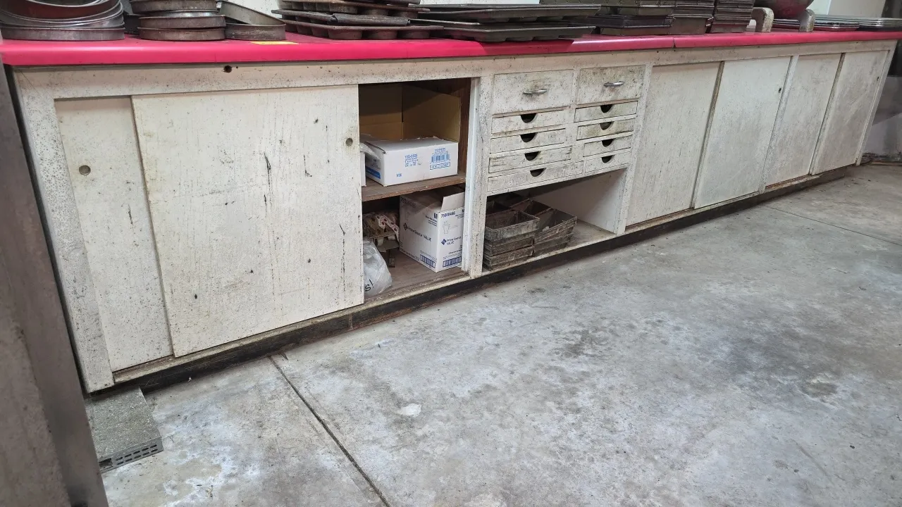 Wood cabinet with laminate top. Features sliding cabinet doors, center multi-drawer section, open storage compartments, and laminate work surface. 183