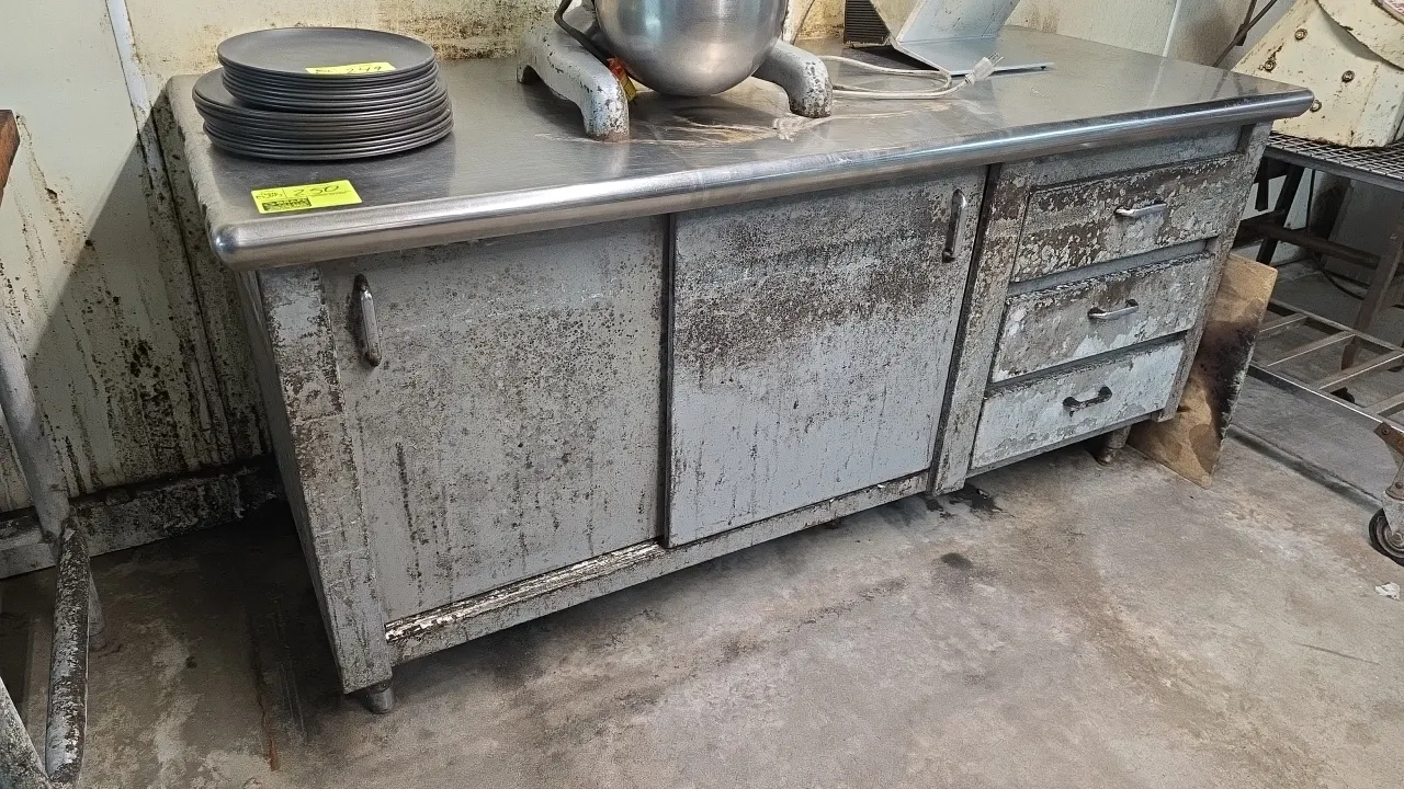 Stainless steel top enclosed work table cabinet. Features a stainless steel work surface with bullnose front edge, two sliding cabinet doors, and thre