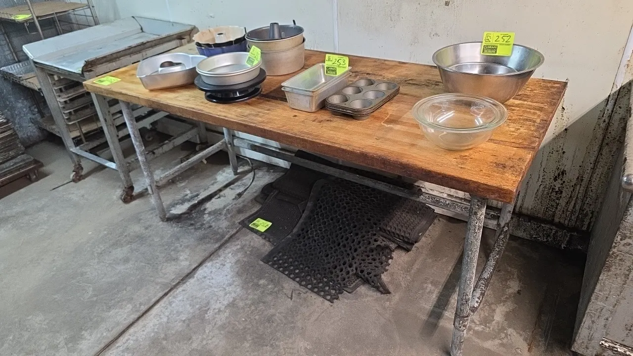 Butcher block work table. Features a solid wood butcher block top and galvanized tubular legs with cross-bracing. 6' x 2'7". Contents and floor mats n